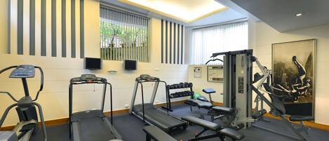 A gym with treadmills, a bench press, dumbbells, and exercise balls.