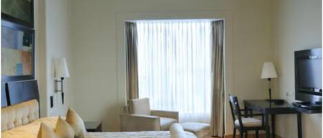 Une chambre d’hôtel avec un grand lit, un bureau, une chaise et un téléviseur.