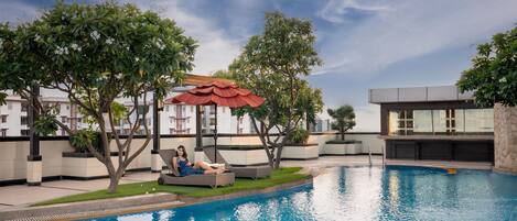 A swimming pool with lounge chairs and a covered seating area.
