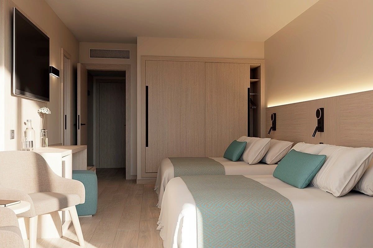 A hotel room with two beds, a desk, a chair, a TV, and a wardrobe.