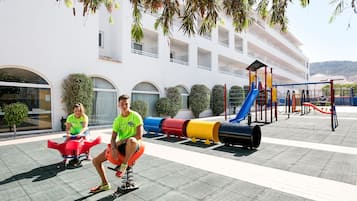 Children can play on the slide, swings, and seesaw in this outdoor play area.