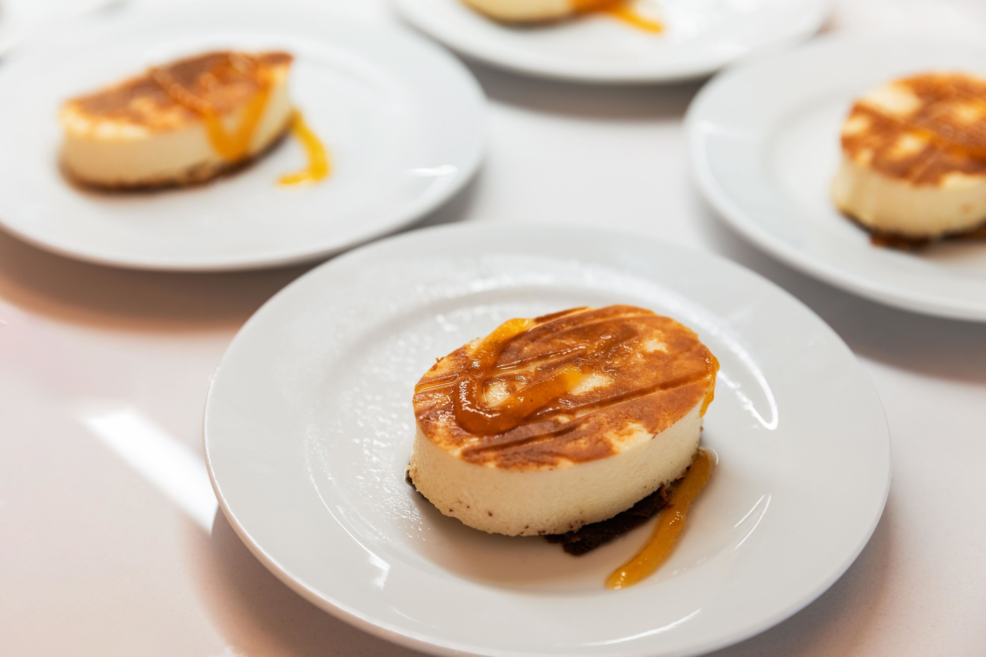 A dessert plate with a caramel-topped dessert, possibly flan or crème brûlée, on a white plate.