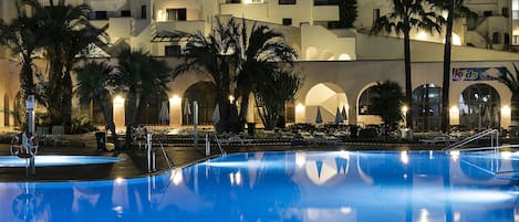 Una piscina al aire libre, sombrillas, sillones reclinables de piscina