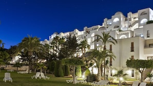 Un hotel d'arquitectura blanca, palmeres i zones d'estar a l'aire lliure.
