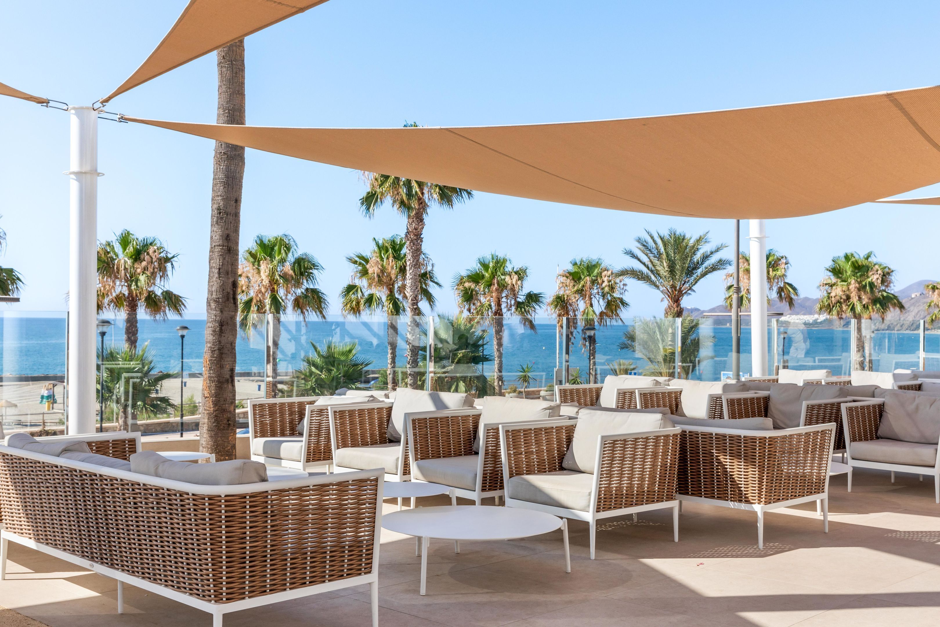 Un área de descanso en la playa con muebles de mimbre y vista al océano.