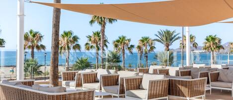 Un área de descanso en la playa con muebles de mimbre y vista al océano.