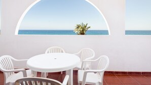 Taula i cadires blanques damunt d'un mur amb una gran finestra apuntada que donava al mar.