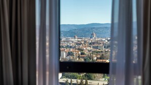 A cityscape through a window with curtains, featuring a prominent dome and a tall tower. - DoubleTree by Hilton Florence Metropole (Florence)