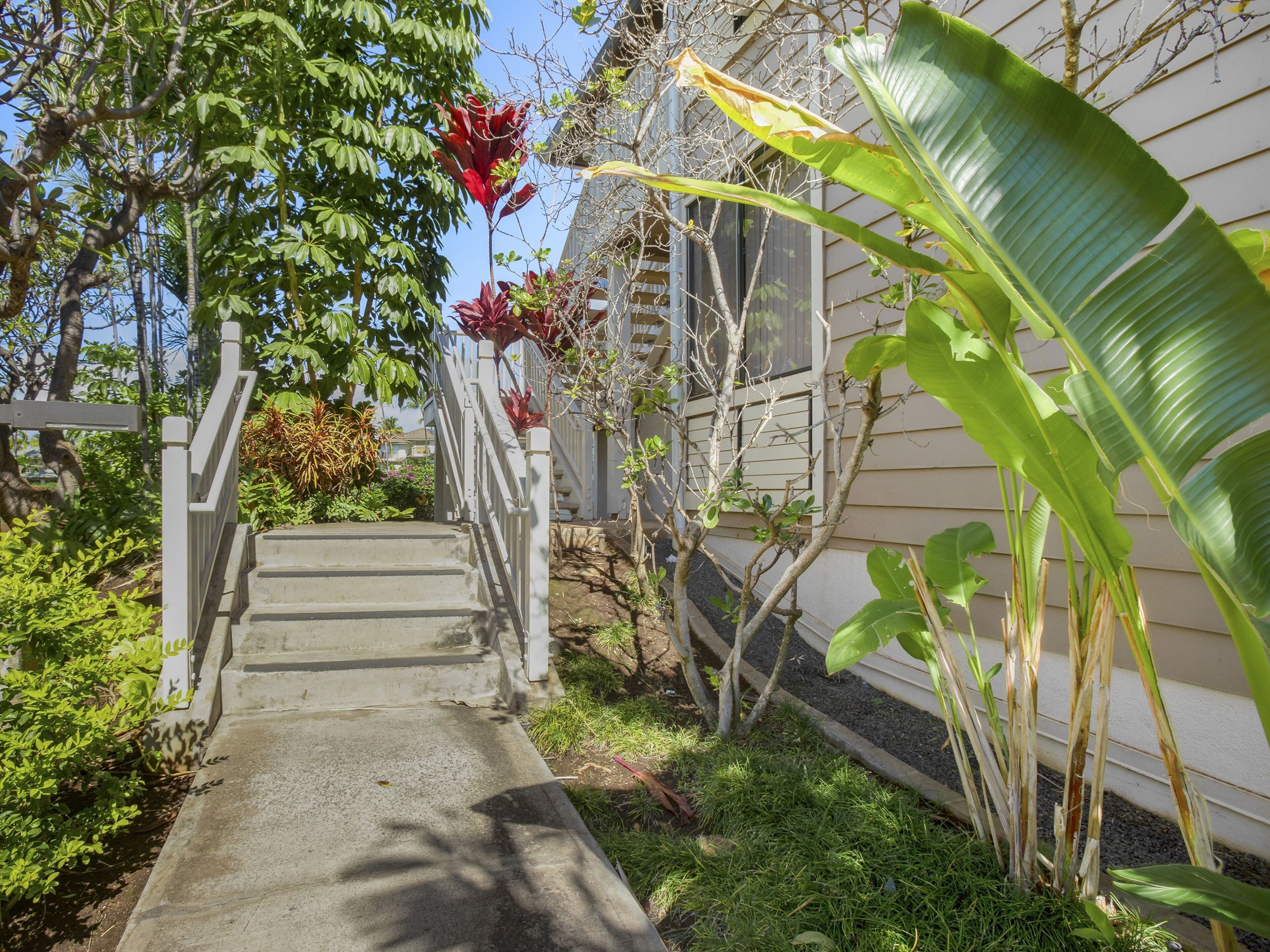A concrete pathway leading to a house with a white railing.