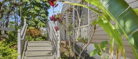 A concrete pathway leading to a house with a white railing.