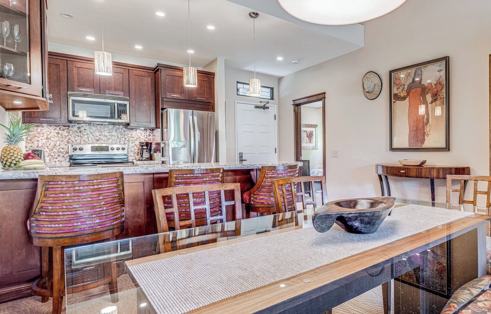 A modern kitchen with wooden cabinets, stainless steel appliances, and a bar area with stools.