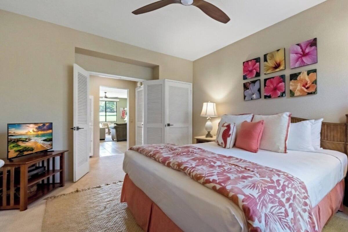 A hotel room with a bed, a television, a lamp, and a view of the outside.