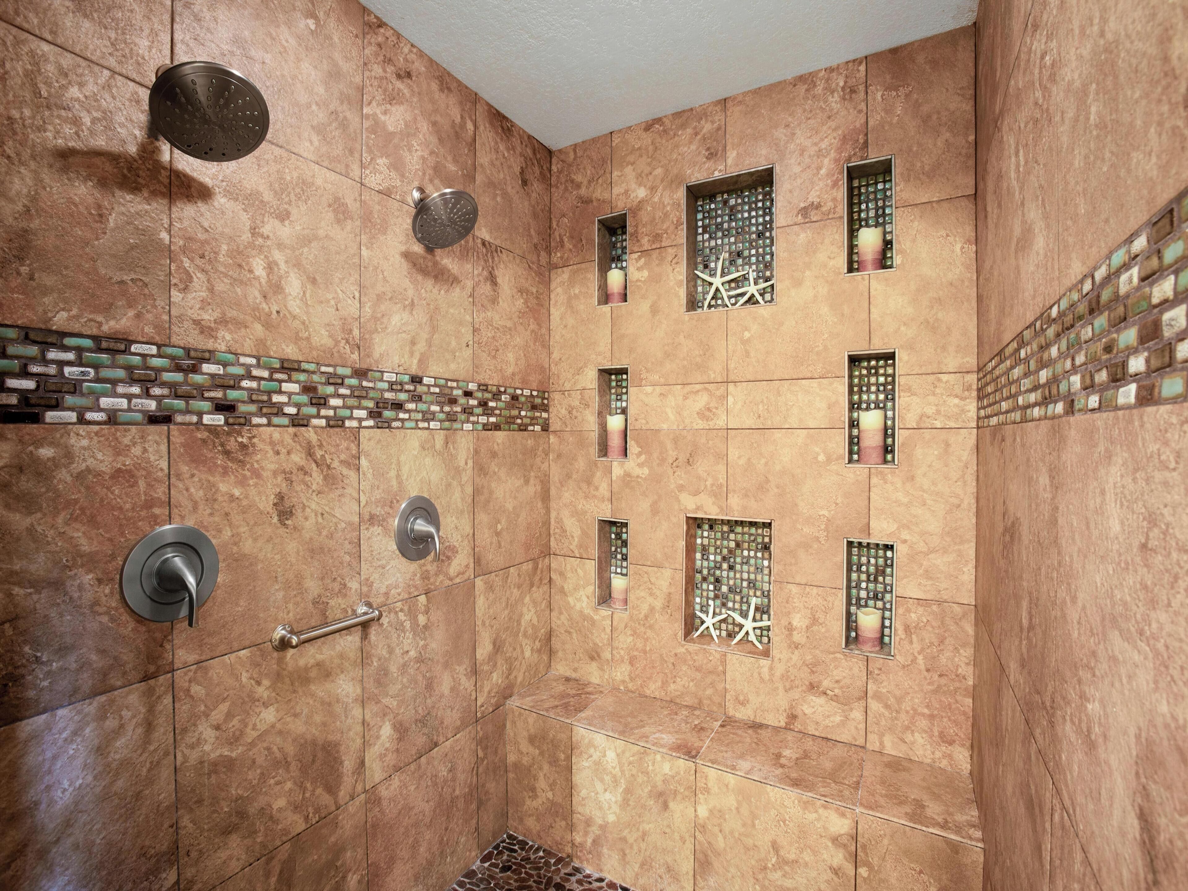 A shower with a rain showerhead, a handheld showerhead, and a handheld faucet.