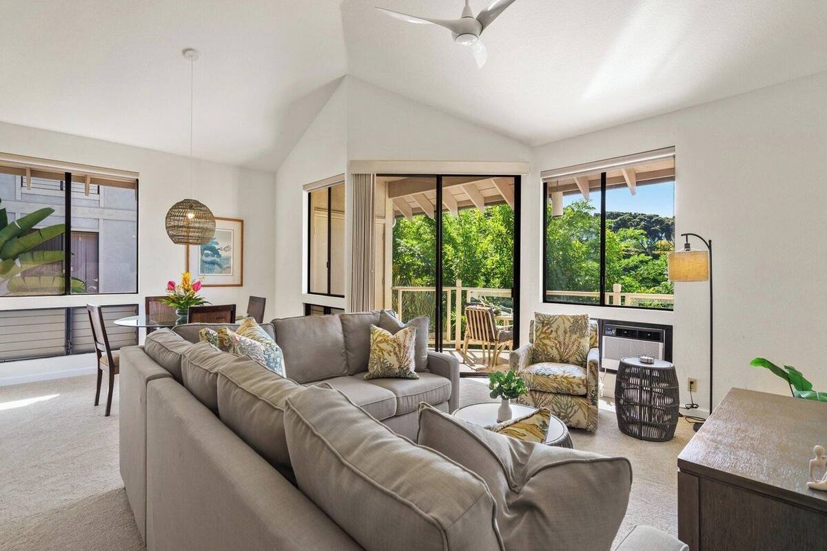 A spacious living area with a large sofa, a dining table, and a view of the outdoors.