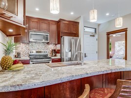 Una cocina moderna con armarios de madera, electrodomésticos de acero inoxidable y encimera de mármol.