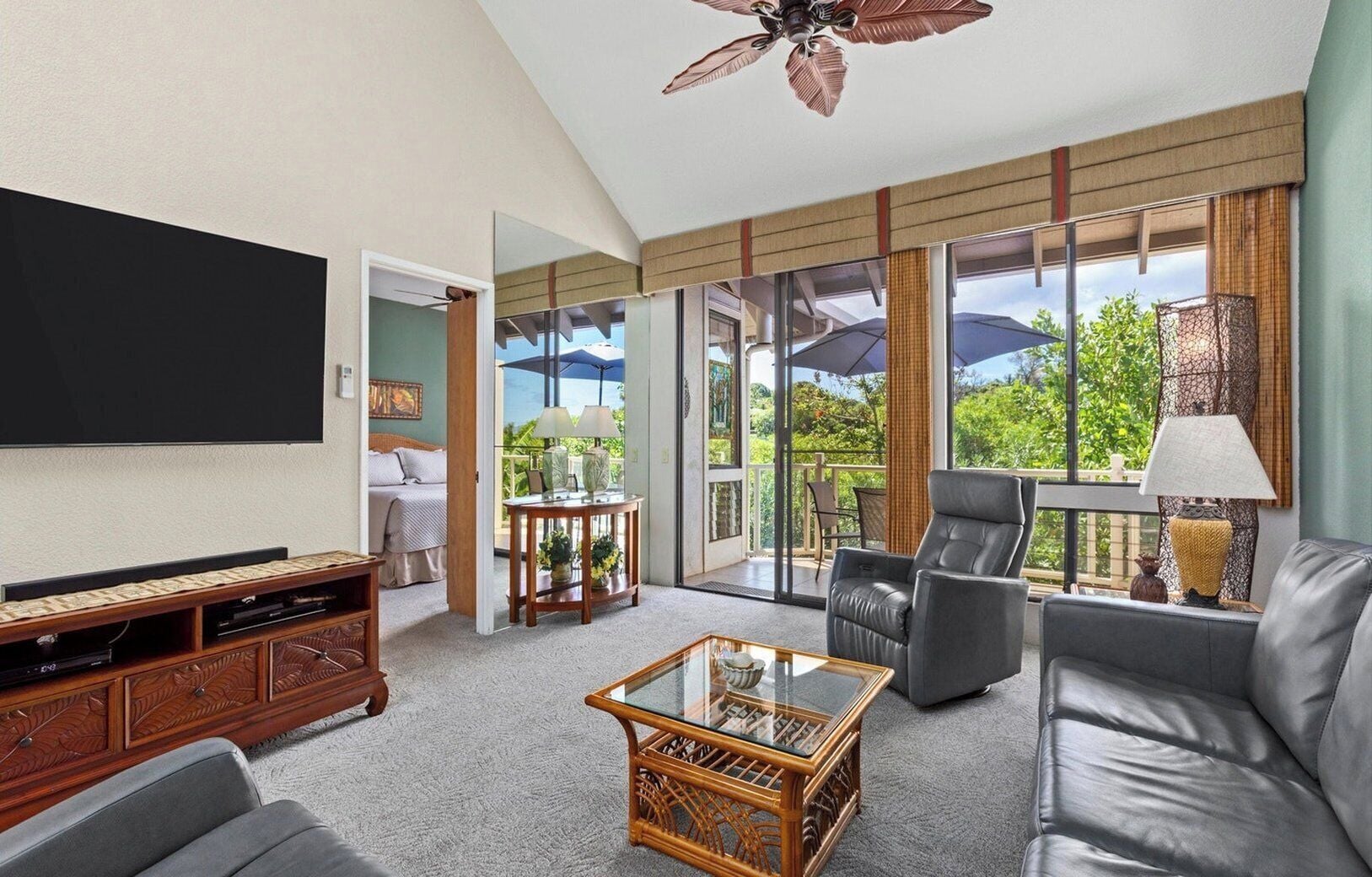 Ein modernes Wohnzimmer mit Flachbildfernseher, einer Couch, einem Couchtisch und einem Balkon mit Gartenmöbeln.