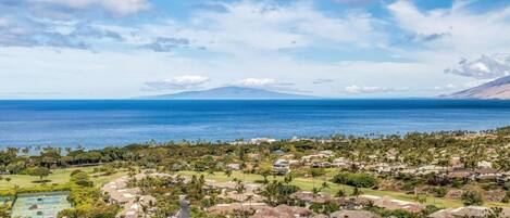 A coastal residential area with houses, a golf course, and a mountain in the background.