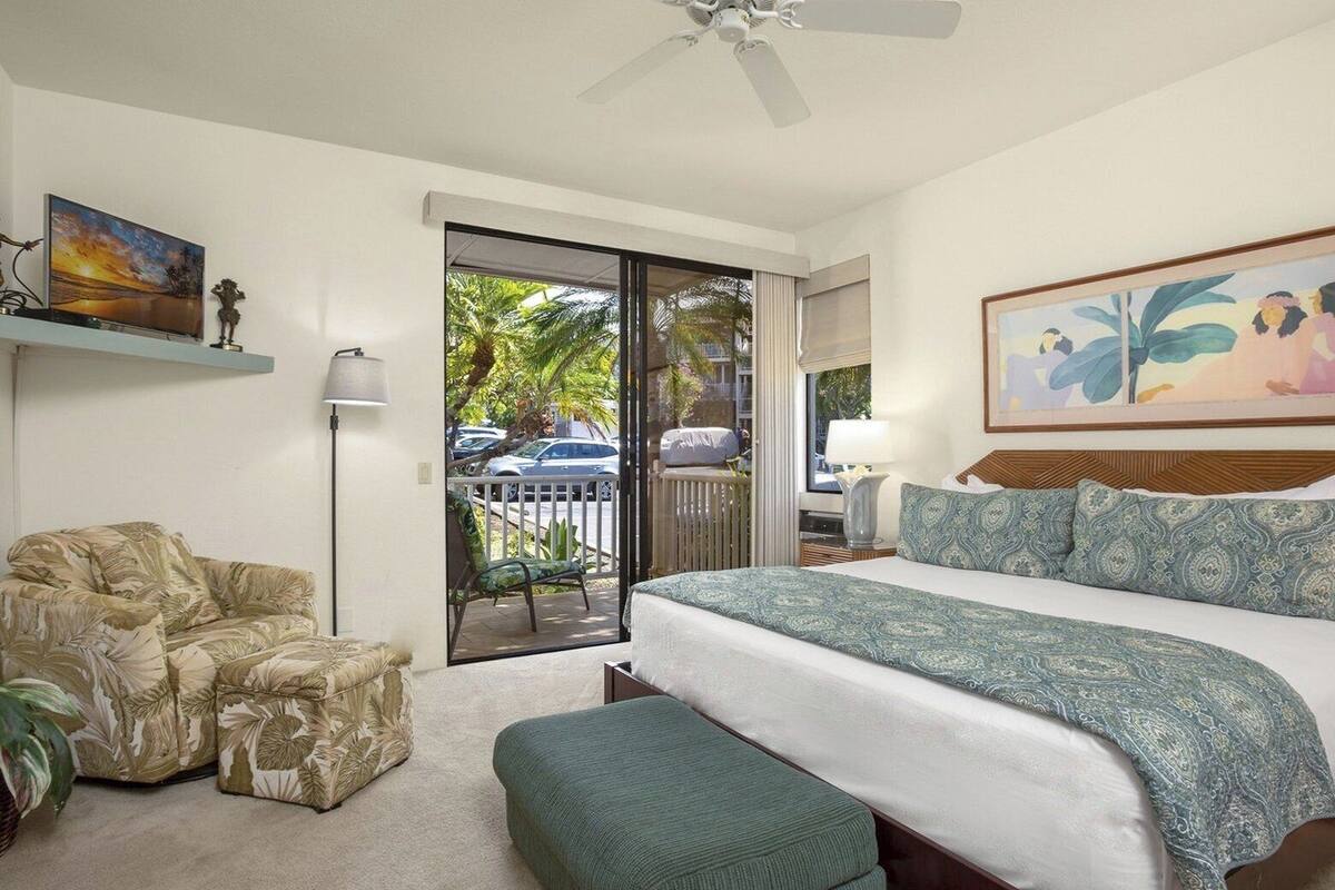 A hotel room with a bed, a chair, a desk, a lamp, and a painting.