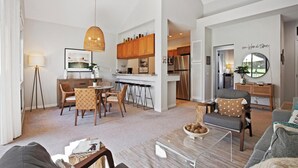 Una sala de estar moderna con comedor, cocina y un espejo grande.