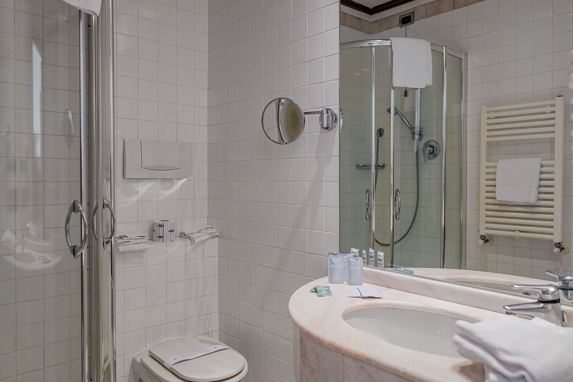 Un baño moderno con cabina de ducha de vidrio, inodoro y tocador con lavamanos y espejo.