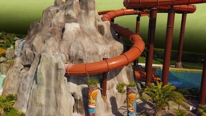 Eine Wasserrutsche vor einer Felslandschaft mit Palmen.