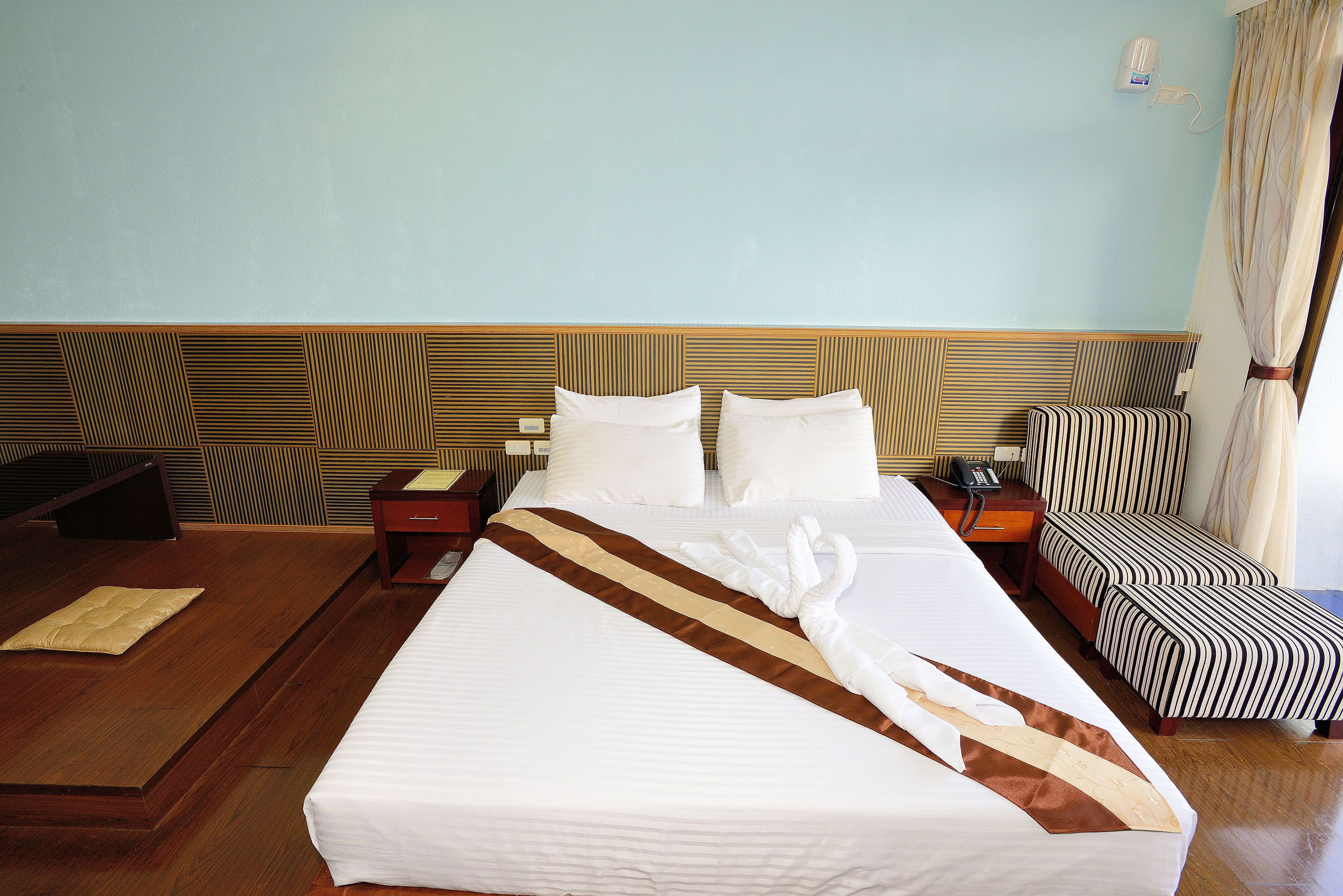 Una camera d'albergo con un letto grande, un comodino, una scrivania, una sedia e un muro decorato.