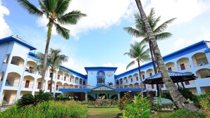 Un hotel de varios pisos con un patio central, palmeras y una decoración en tonos azul y blanco.