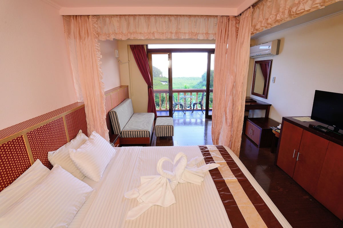 Ein Hotelzimmer mit Bett, Fernseher, Schreibtisch und Balkon mit Aussicht.
