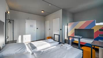 Ein Hotelzimmer mit zwei Einzelbetten, einem Schreibtisch, einem Stuhl und einer farbenfrohen Wanddekoration.