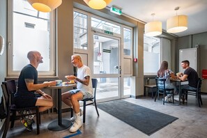 Un espace de restauration intérieur moderne, doté de grandes fenêtres, d’une porte portant l’inscription « SMB » et d’un panneau de signalisation indiquant clairement la sortie.
