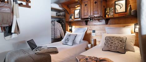 Una habitación acogedora con dos camas, un ordenador portátil sobre una de ellas, y una manta en el suelo.
