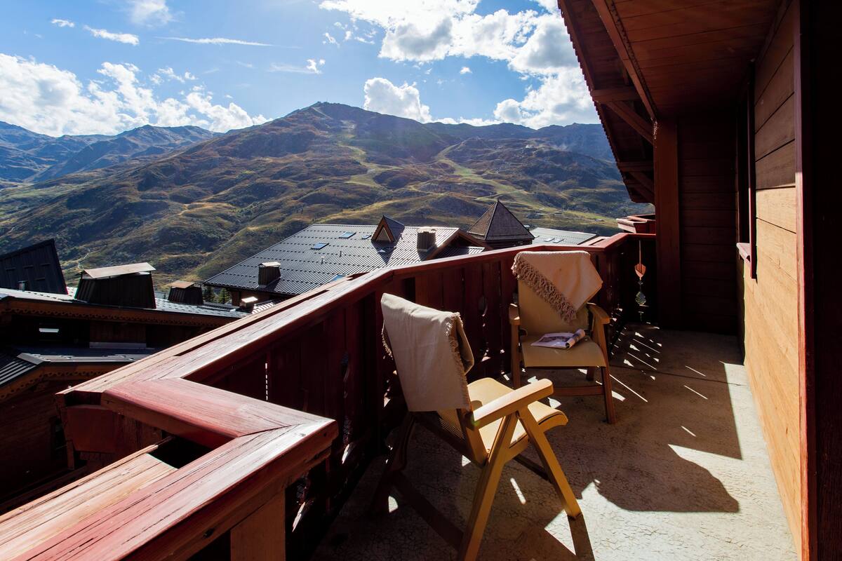 Eine Holzterrasse mit Blick auf Berge, einem Stuhl und einem Tisch.