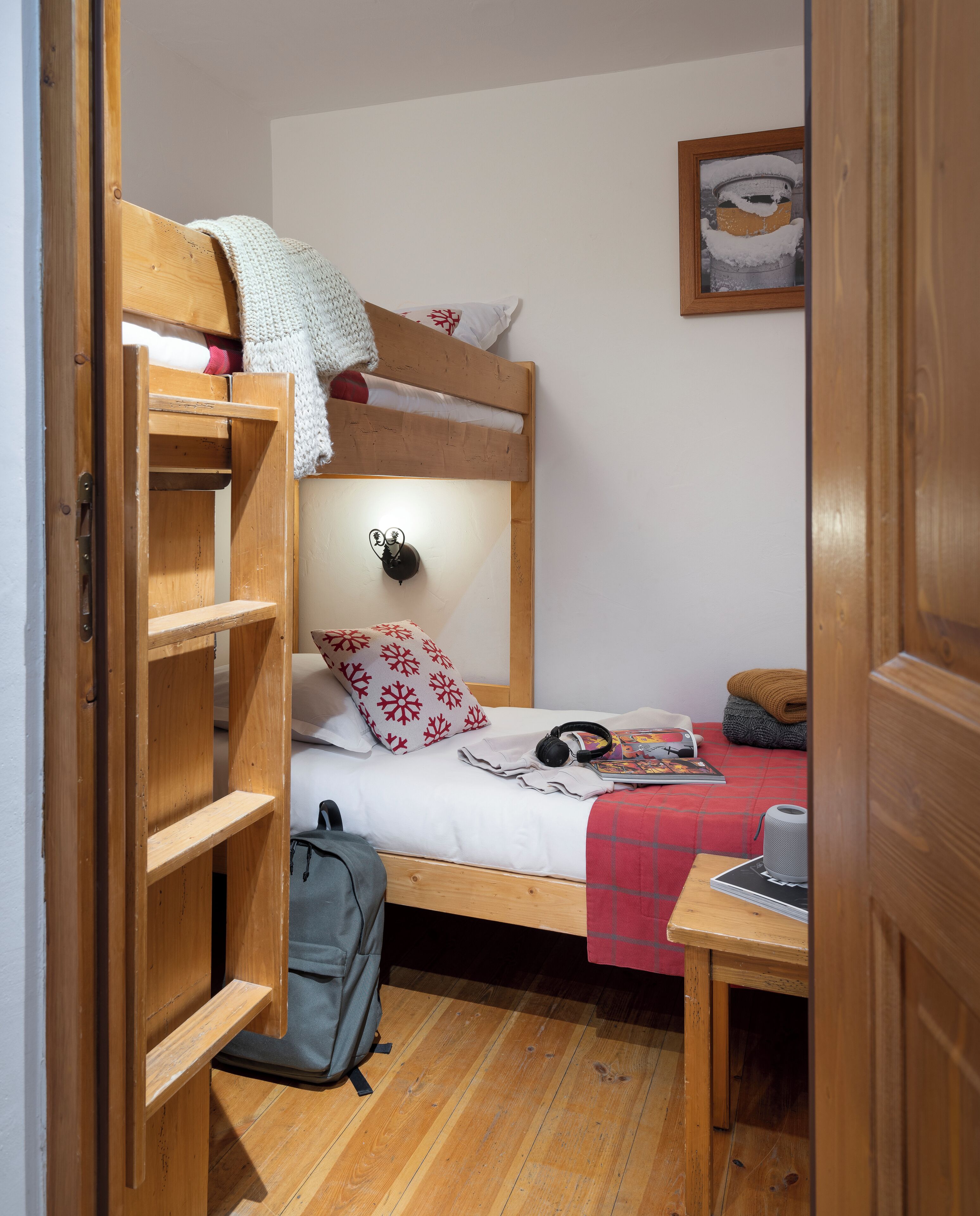 Ein kleiner, gemütlicher Raum mit einem Etagenbett, einem Nachttisch, einer Lampe und einem gerahmten Bild an der Wand.