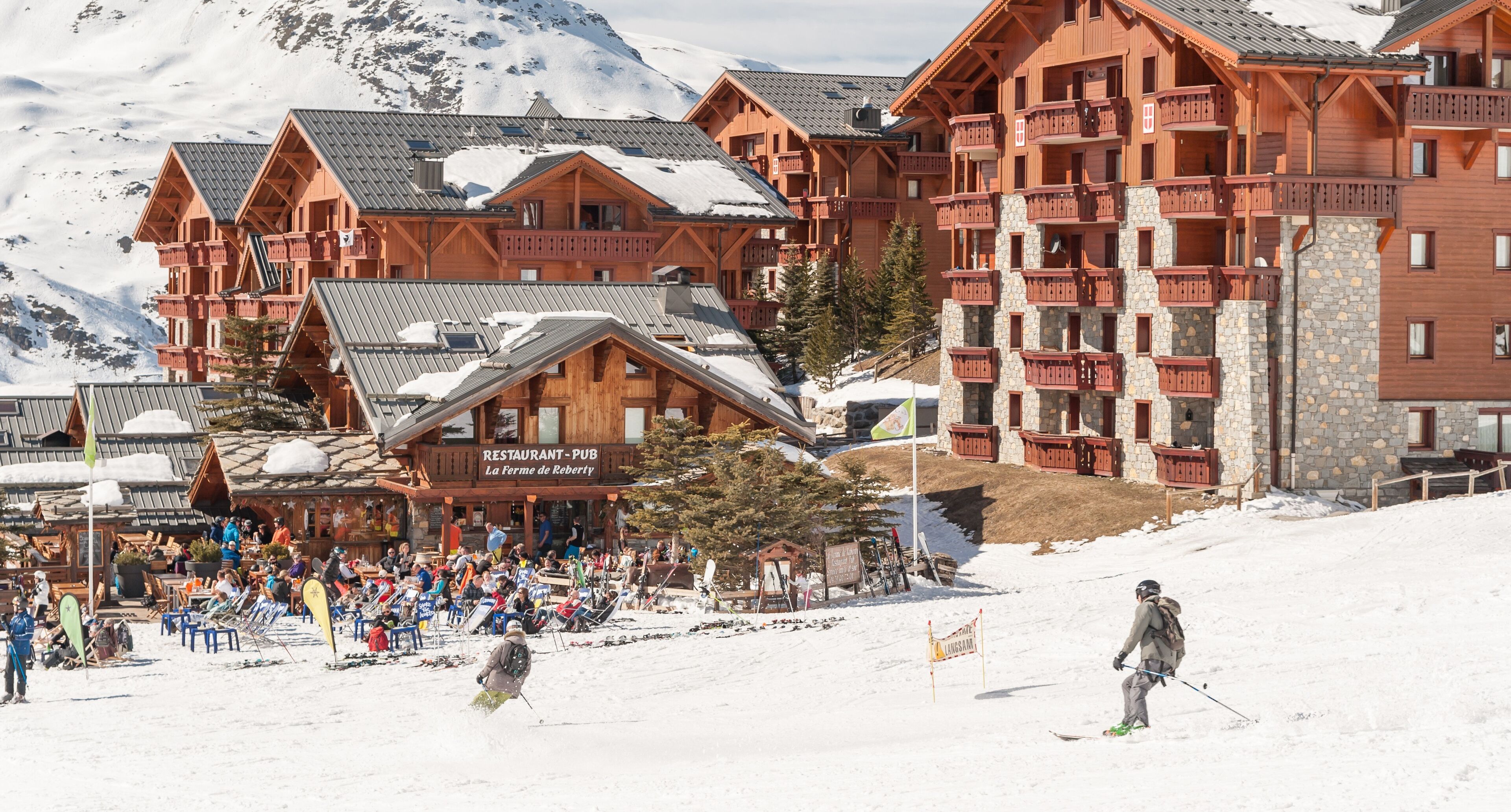 A ski resort with wooden buildings, a restaurant, and a ski slope.