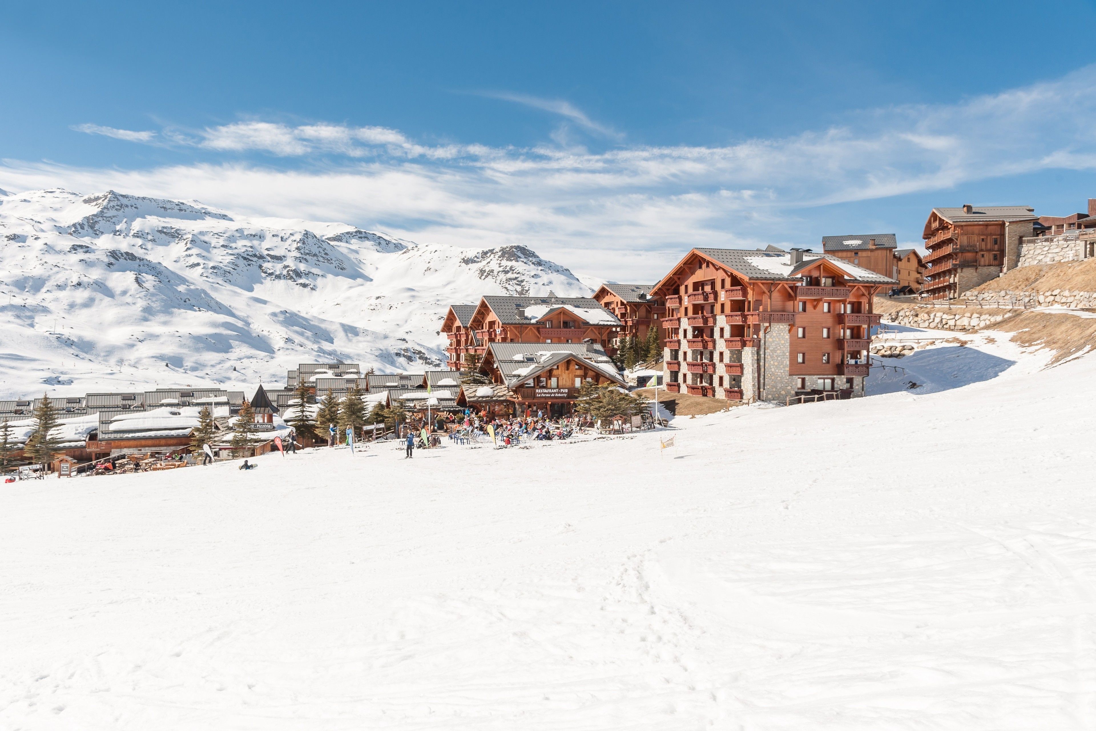 Una località montana innevata con edifici in legno e una pista da sci.