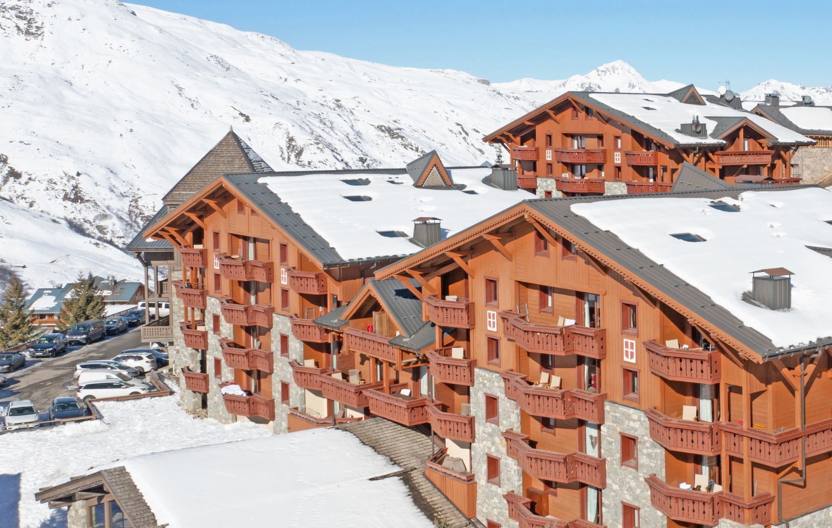 Un chalet de madera de varios pisos con balcones, con vista a una montaña nevada.