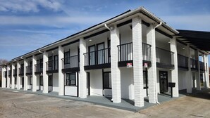 Een rij witte gebouwen van baksteen met zwarte leuningen en een plat dak.