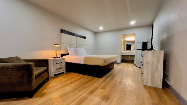 Een moderne slaapkamer met een bed, nachtkastje, lamp en een zithoekje.