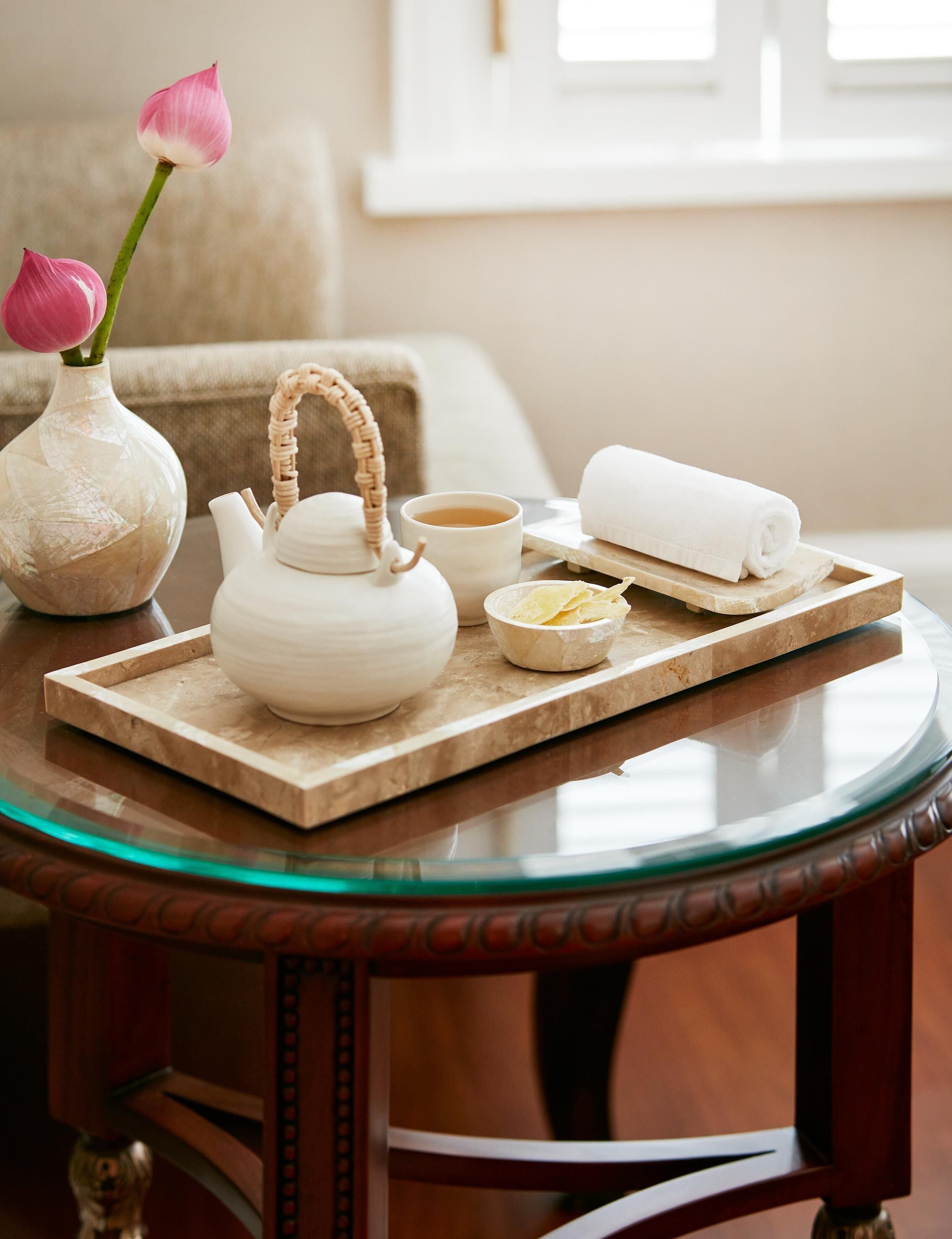 Una mesa con tetera, taza y toalla enrollada, indicando una disposición para servir té.