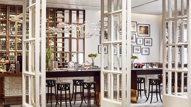 A spacious room with a large open area, a bar with stools, and a view through a glass partition.