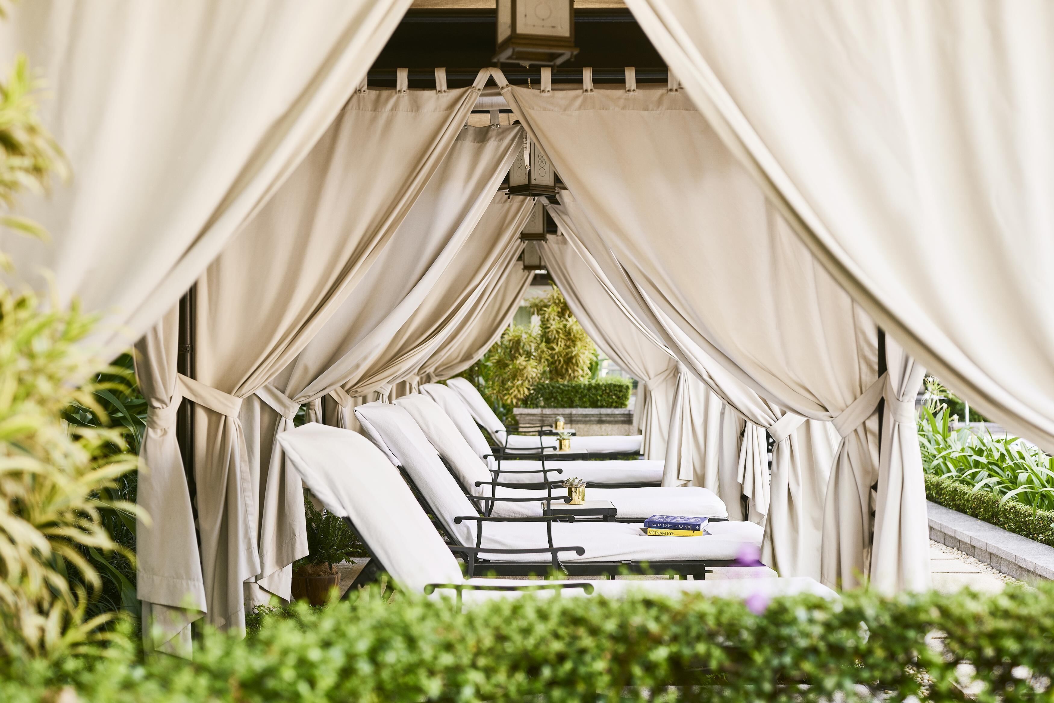 Filas de sillones de descanso bajo una pérgola con vista a la vegetación.