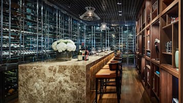 A bar area with a marble counter, wine glasses, and bottles.
