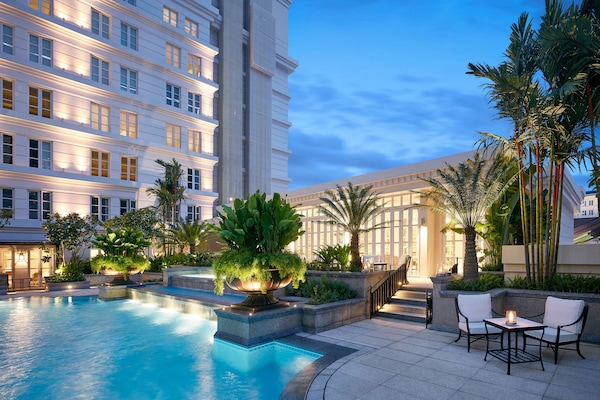 Una piscina al aire libre, sombrillas, sillones reclinables de piscina