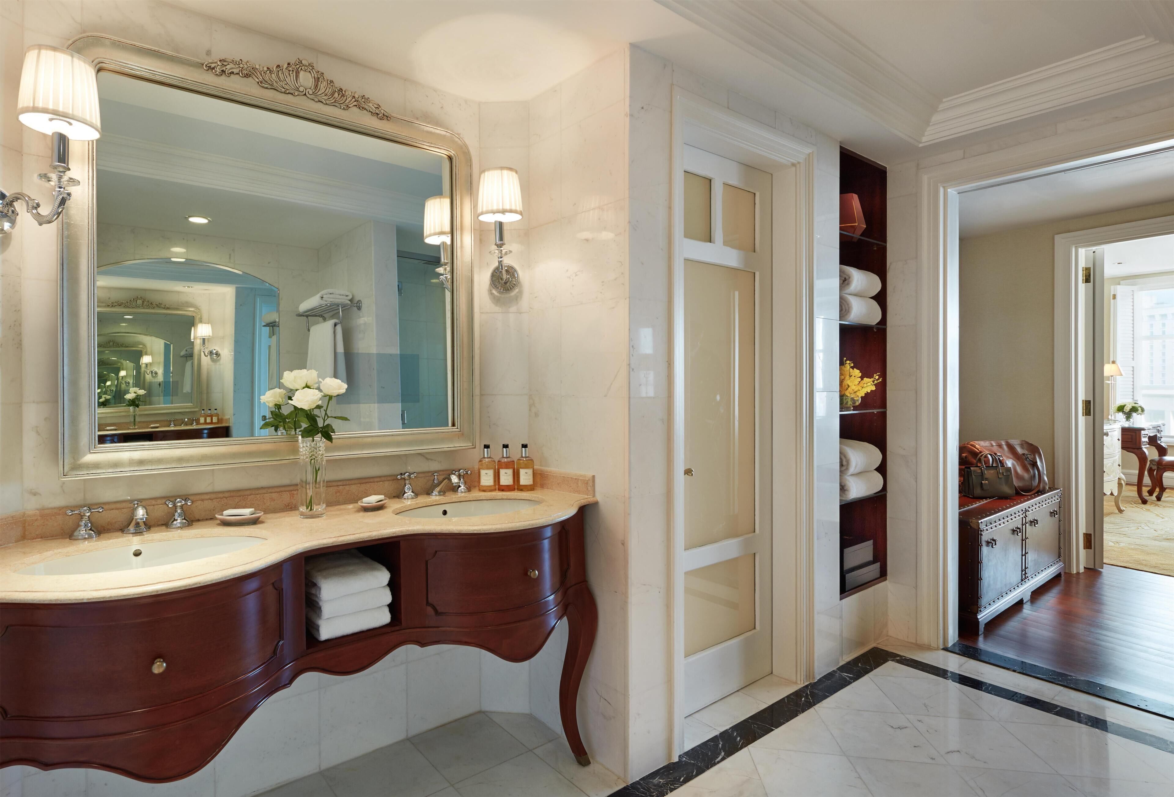 Un baño lujoso con un espejo grande, lavamanos dobles y un mueble de tocador con espacio de almacenamiento.
