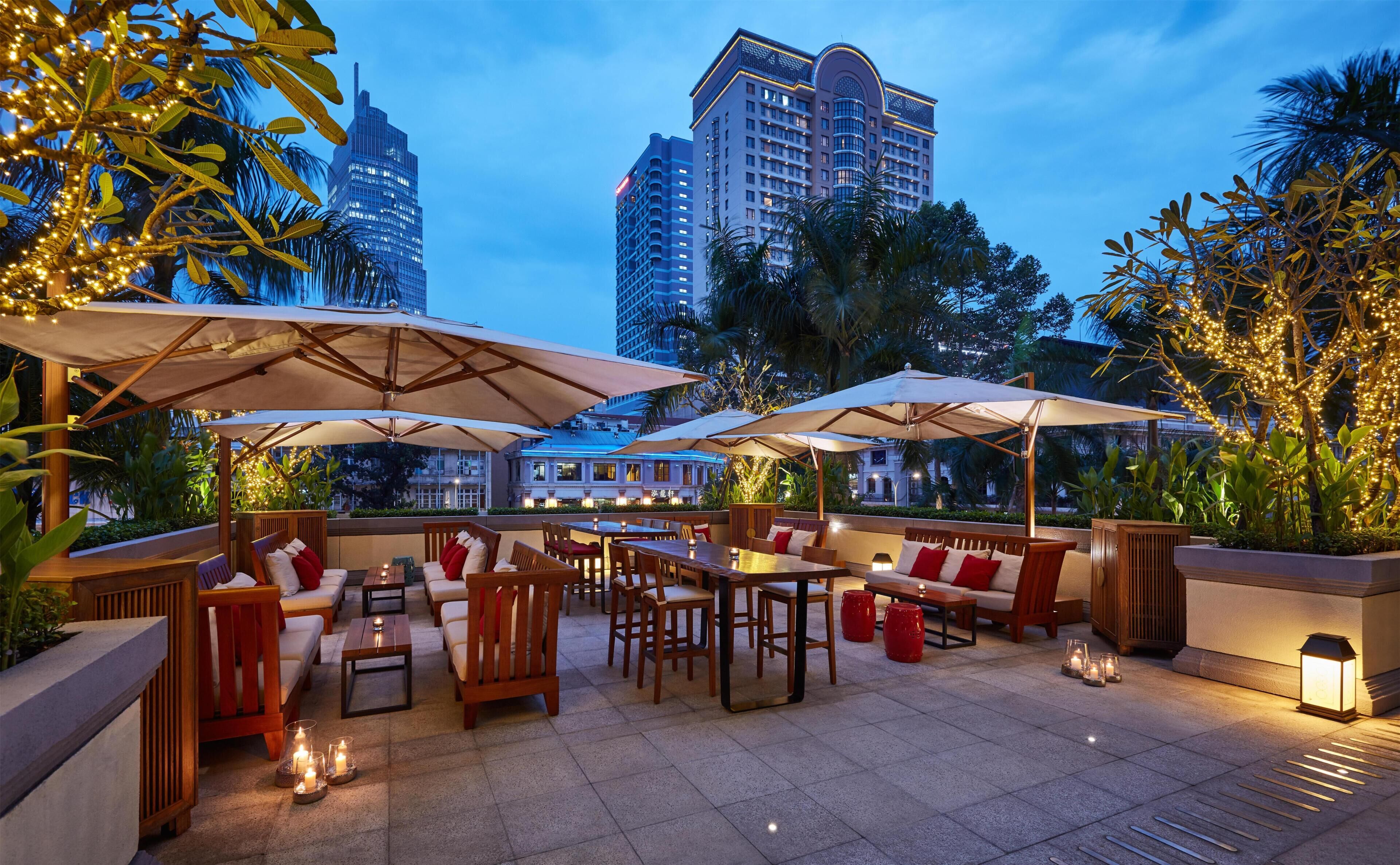 An outdoor seating area with tables and chairs, umbrellas, and candles.