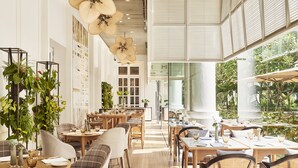 A spacious dining area with high ceilings, large windows, and a variety of seating arrangements. - Park Hyatt Saigon (Ho Chi Minh City)