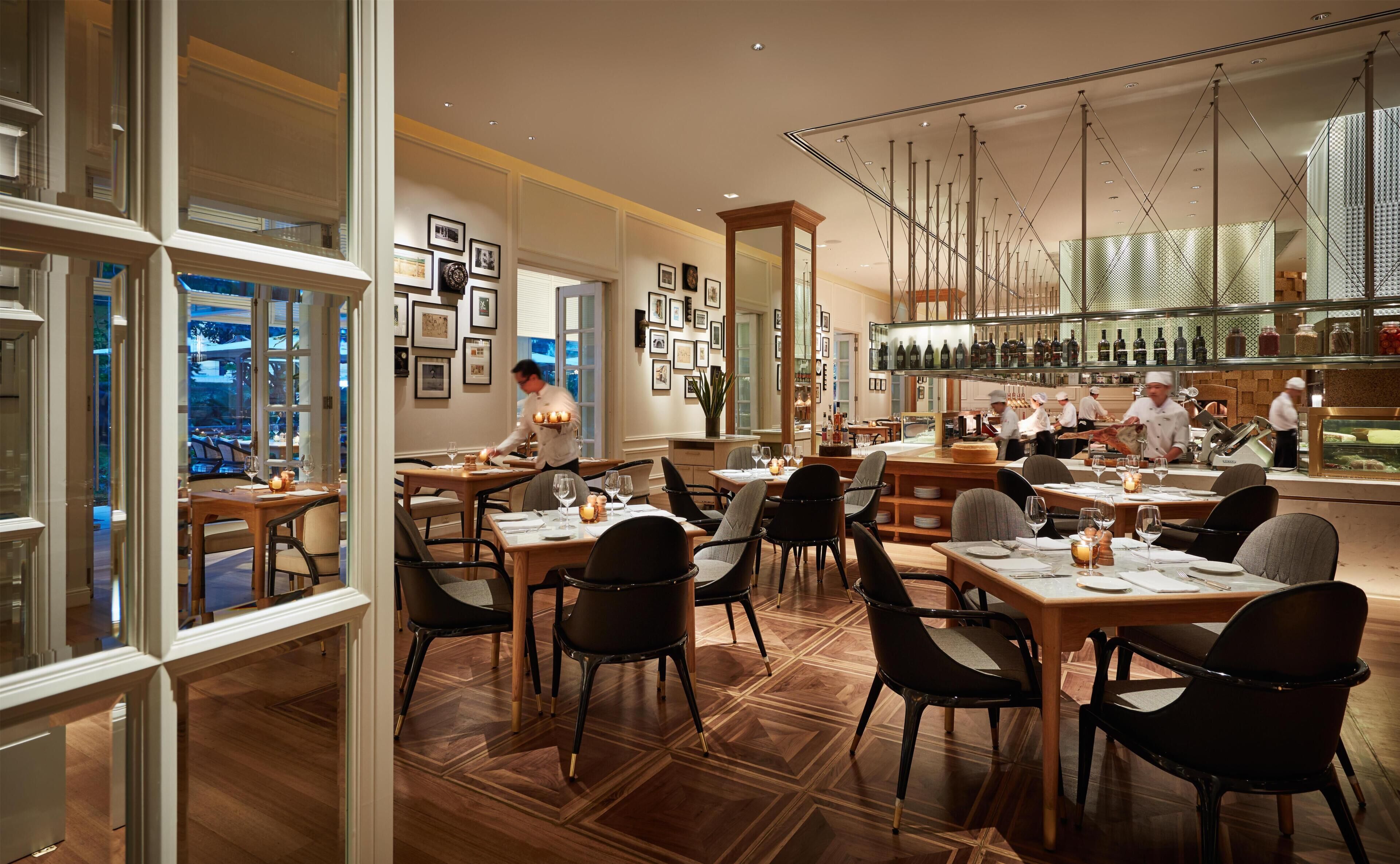 Un restaurant doté de plusieurs tables, de chaises et d’un comptoir où le chef prépare les plats.