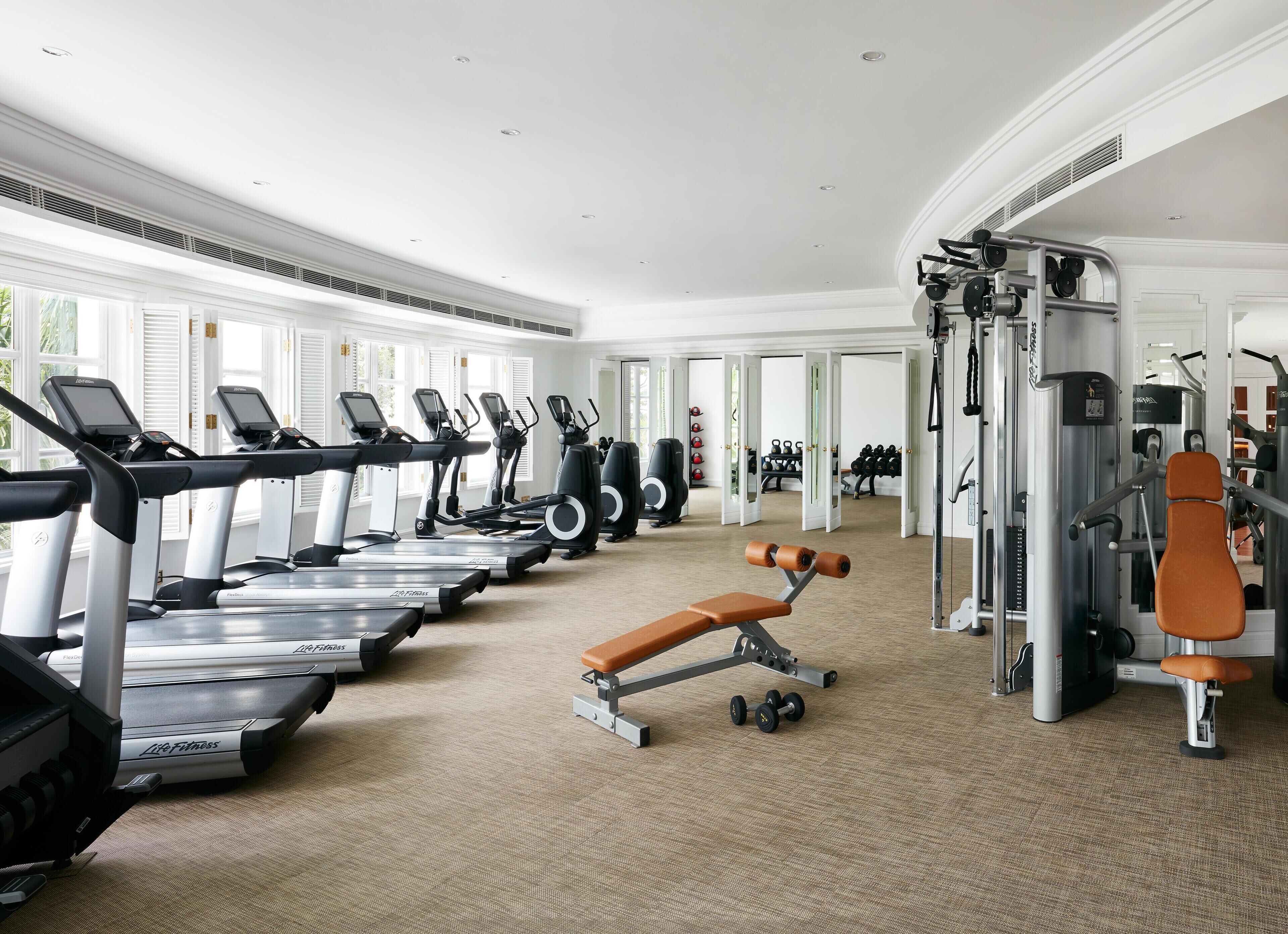 A gym with treadmills, weight machines, and a bench.