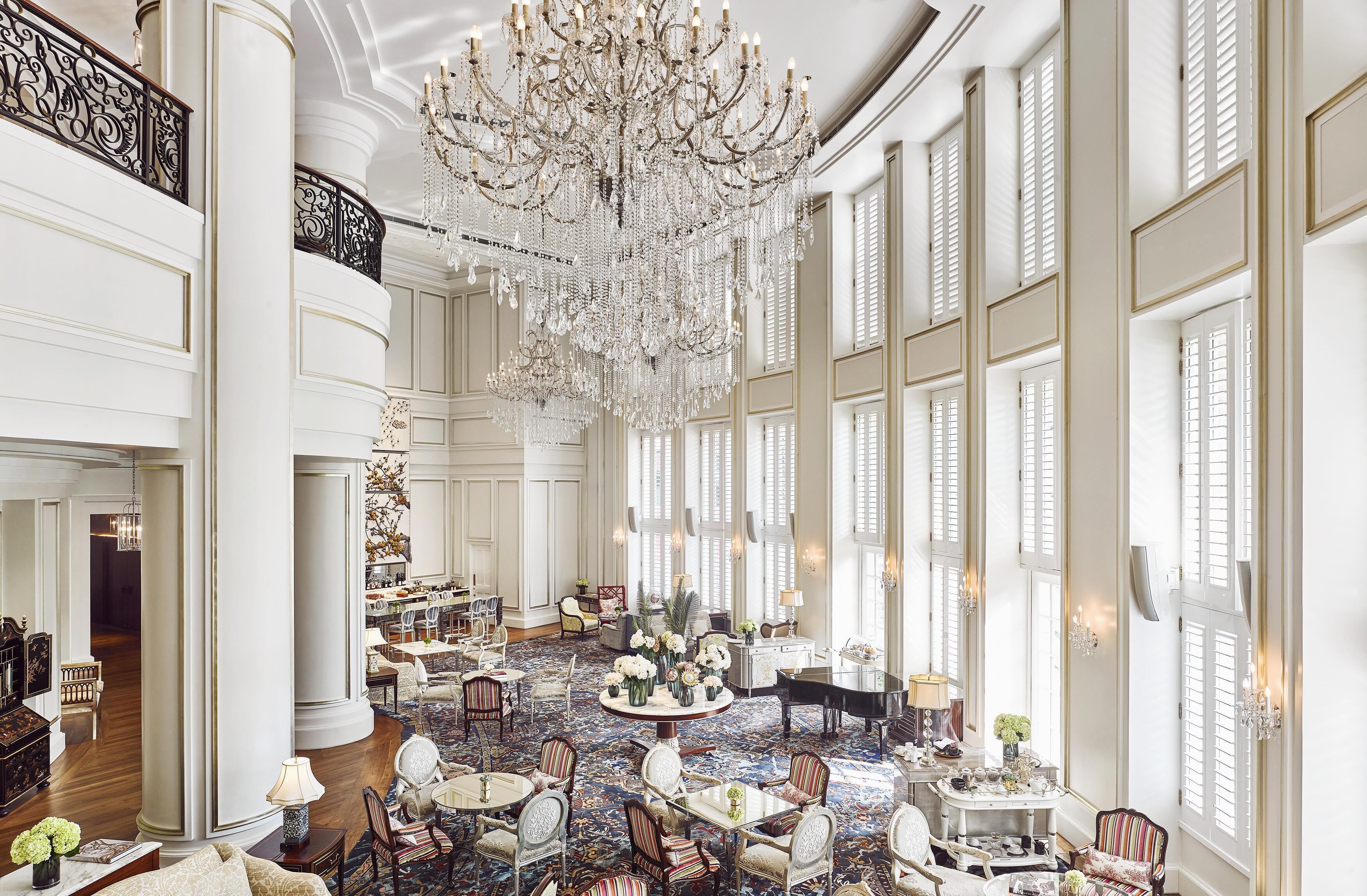 A grand lobby with a large chandelier, multiple seating areas, and a piano.
