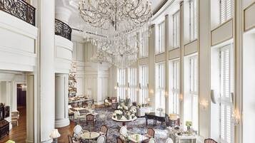 A grand lobby with a large chandelier, multiple seating areas, and a piano.